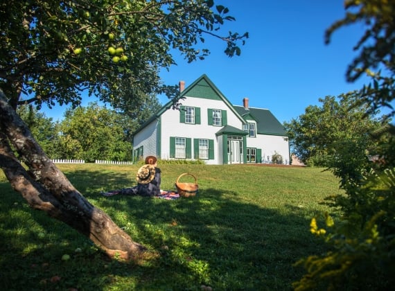 An Anne of Green Gables reenactor poses outside the house